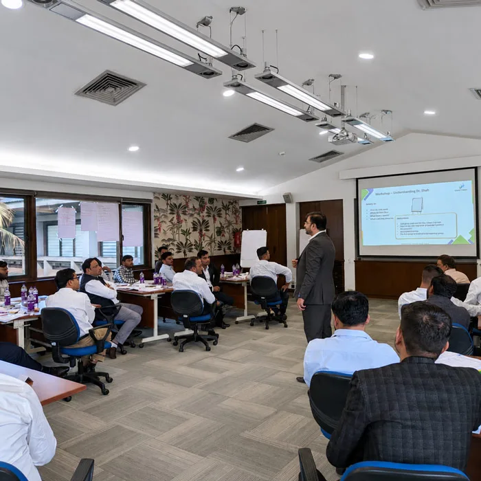 A corporate IT sales training workshop with a trainer presenting to a group of executives.